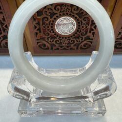 Polished jade bangle framed by ornate panel
