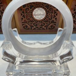 Crystal ring holder with intricate wooden background.