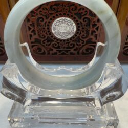 Jade bracelet on ornate wooden display stand.