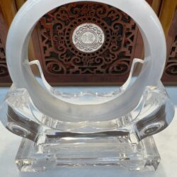 Crystal bracelet displayed on ornate wooden stand.