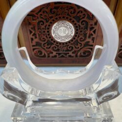 Jade circle sculpture on intricate wooden background.