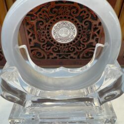 Circular crystal sculpture with intricate background design.