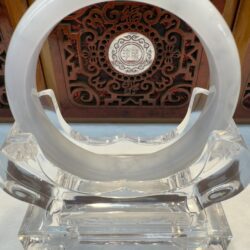 Round jade ring displayed before ornate wooden panel