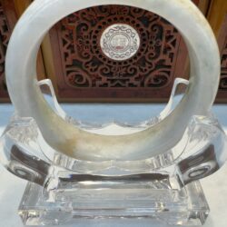 White jade bracelet on a transparent stand.