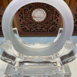 Milky white jade bangle against carved wood