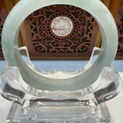 Green jade bangle on crystal stand display.