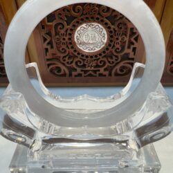 Clear circular stand with intricate background design.