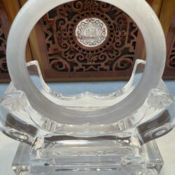Circular jade ornament on ornate wooden stand.