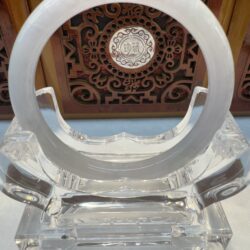 Crystal display stand with intricate wooden background.