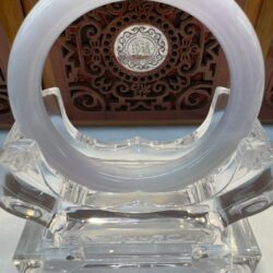 Translucent jade ring on carved display stand.
