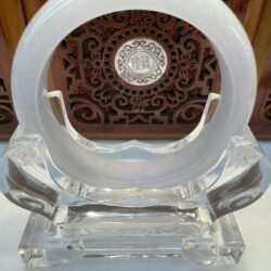 Circular jade ornament with intricate wooden background.