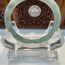 Green jade bangle centered against carved wood