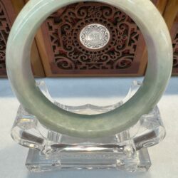 Glossy green jade bracelet on clear holder