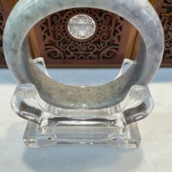 Gray-green jade bangle on clear acrylic stand