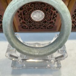 Smooth pale green jade bangle on stand