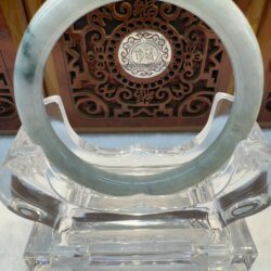 Greenish jade ring framed by ornate panel