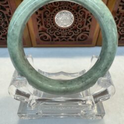 Smooth light-green jade circle perched on clear display
