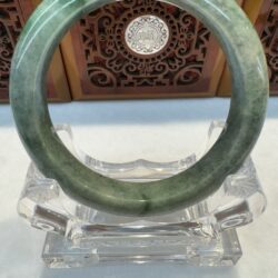 Green jade bangle centered on acrylic stand