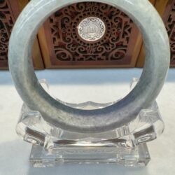 Translucent grey jade bangle on acrylic stand
