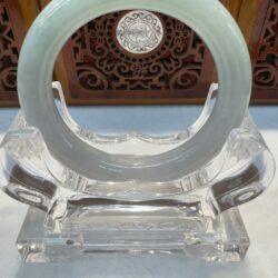 Translucent jade bracelet displayed with carved backdrop