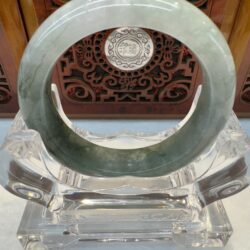 Deep celadon round jade bangle displayed upright