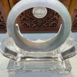 Thick circular jade bracelet in ornate wooden setting