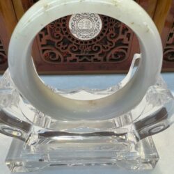 Round white jade bracelet with certificate backdrop