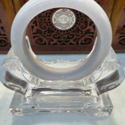 Round jade bangle in carved wood backdrop