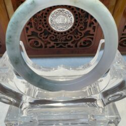 Circular jade bangle framed by wooden carving