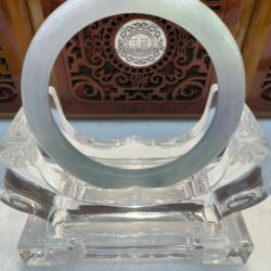 Circular jade bangle framed by ornate wooden panel