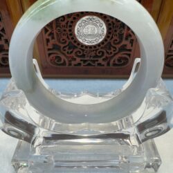 Light jade ring with carved wooden backdrop
