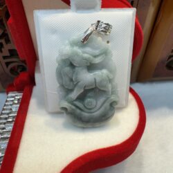 Jade pendant with intricate carving displayed.