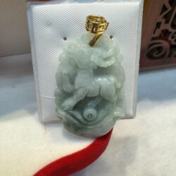 Jade pendant with gold loop on display.