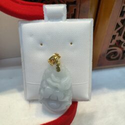 Jade pendant on white display stand.