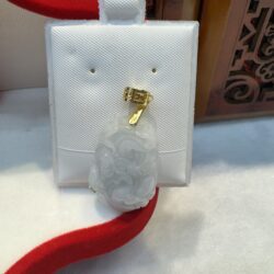 Jade pendant with gold clasp on display.