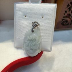 Jade pendant on white display stand.