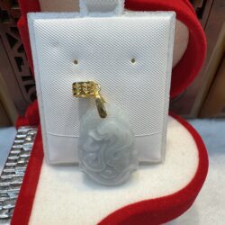 Jade pendant with gold bail on display.