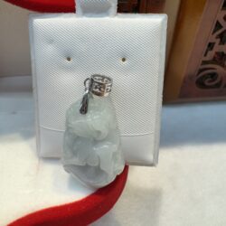 Jade pendant on white display stand.