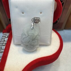 Jade pendant with intricate carving on display.