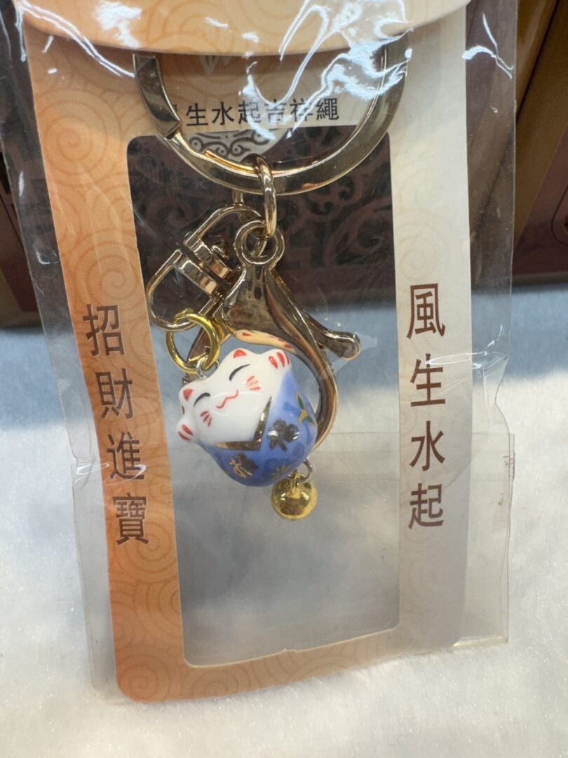 Lucky cat keychain in packaging with text.