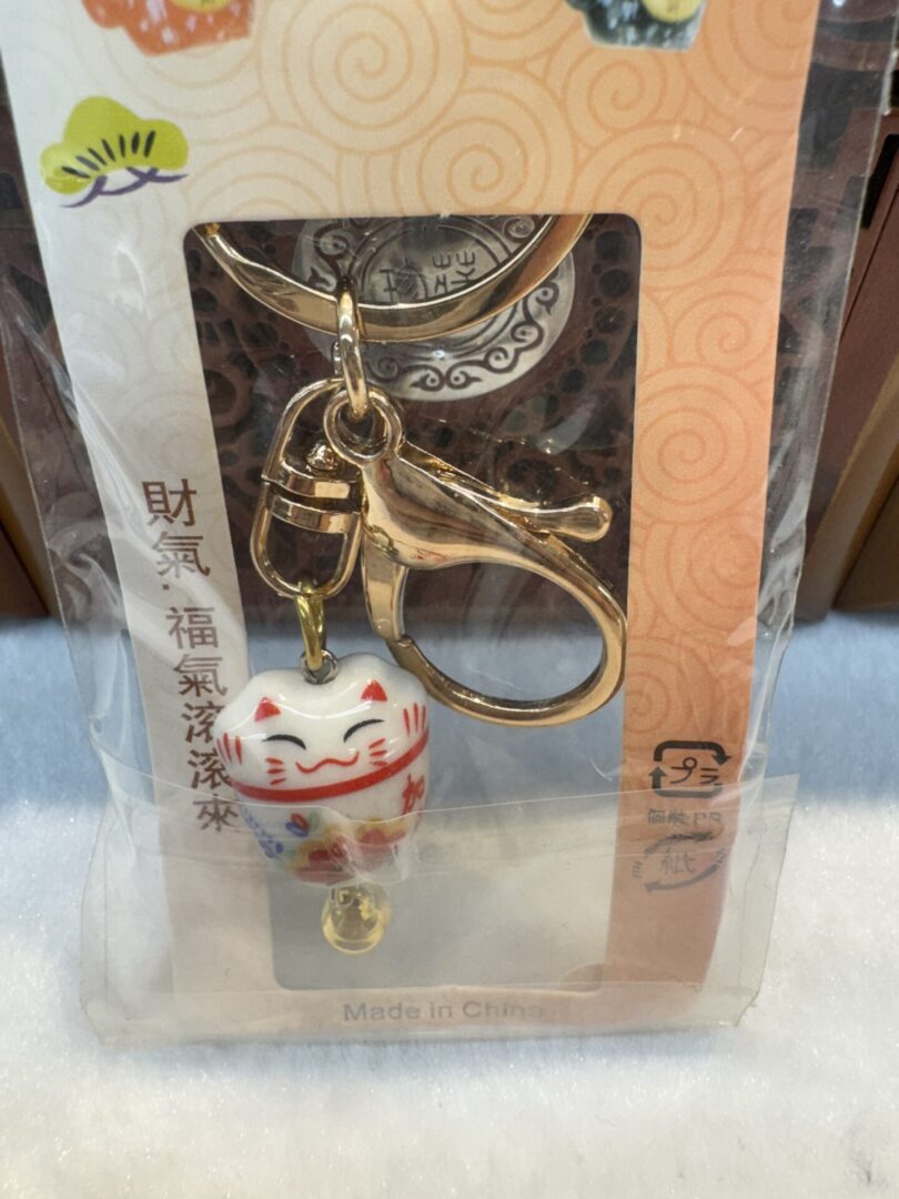 Maneki-neko keychain in plastic packaging.