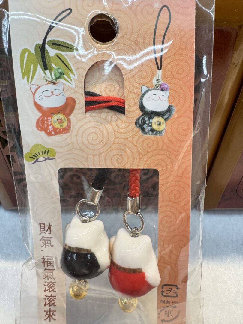Maneki-neko charms in red and black packaging.