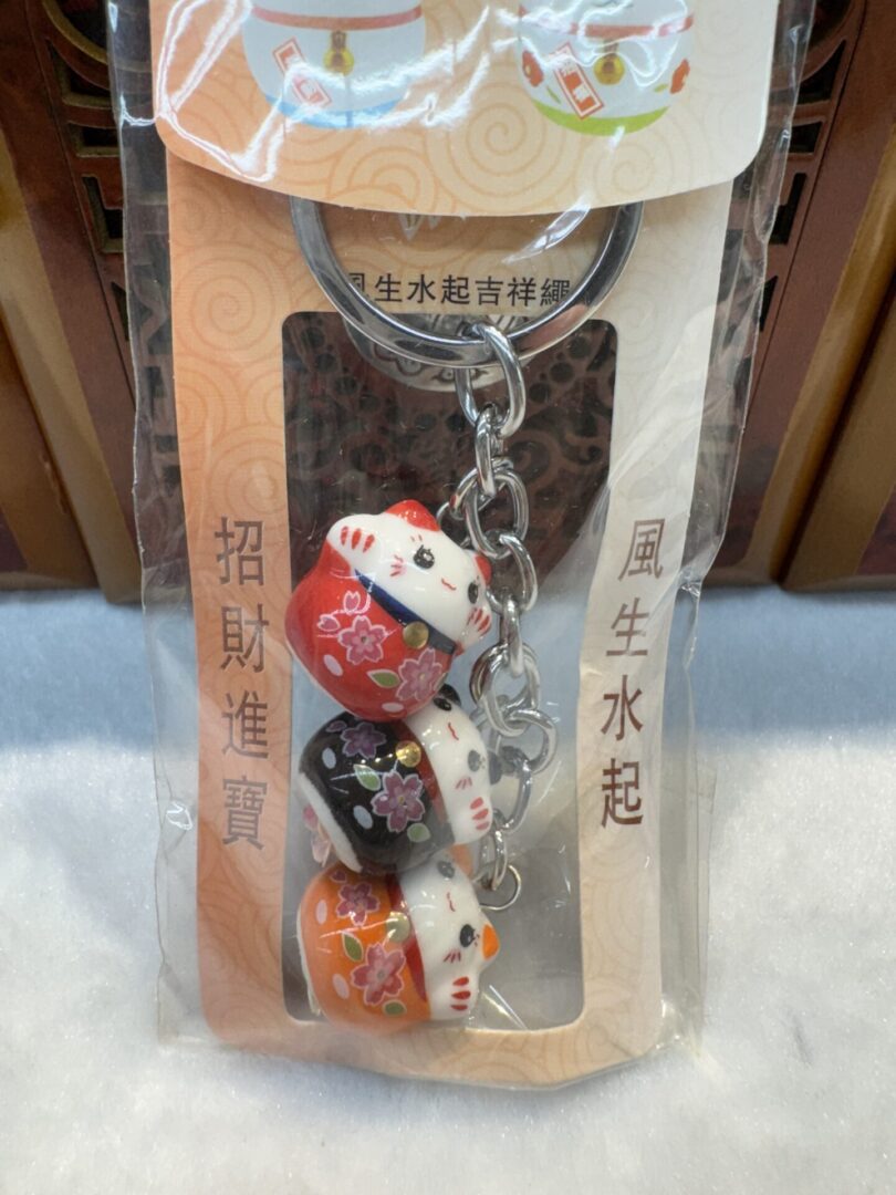 Lucky cat keychain with three figurines.