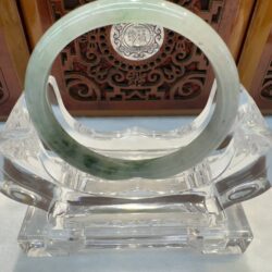 Jade bracelet on a carved wooden stand.