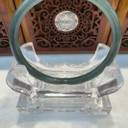 Green ring on ornate wooden background display.