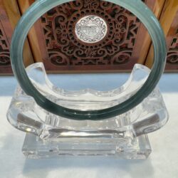 Glass bangle on ornate wooden background.