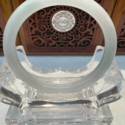Polished light-green jade bracelet on crystal stand