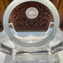 Round pale jade bracelet framed by carved panel