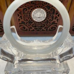 Translucent white jade bangle on crystal stand