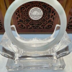 Jade circular ornament on clear stand.